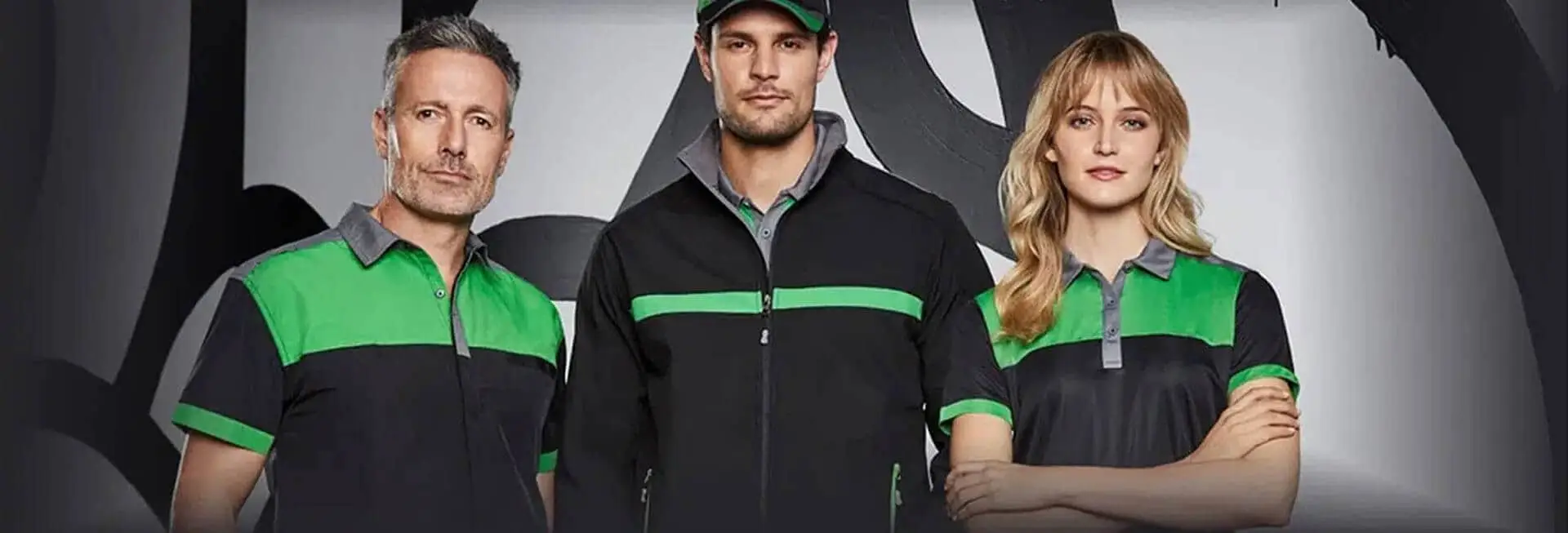 Three individuals wearing black jackets with green stripes and caps, standing together with a neutral background.