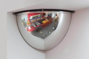 Quarter-sphere convex safety mirror mounted in a corner to provide a wide-angle view of a workshop area.